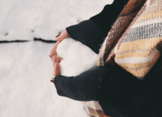 woman in a black sweater holding a heart made out of snow