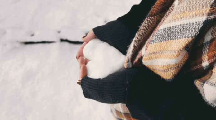woman in a black sweater holding a heart made out of snow