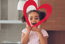 Young girl holding a heart paper.