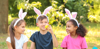 three kids wearing bunny ears holding easter eggs