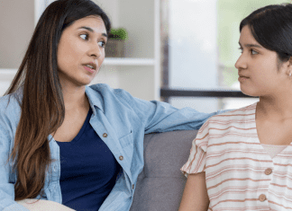 Mom and Teen daughter sitting on couch talking to each other