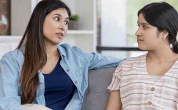 Mom and Teen daughter sitting on couch talking to each other