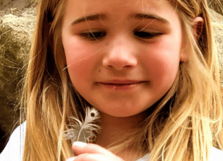 young girl holding a feather she found while hikinh