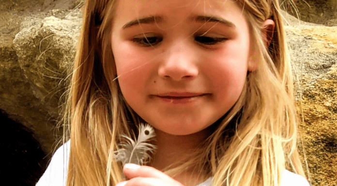 young girl holding a feather she found while hikinh