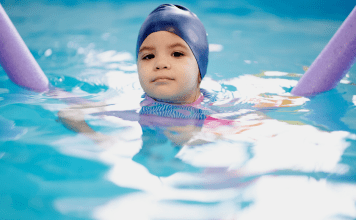 child in a swim cap in a pool during swim class