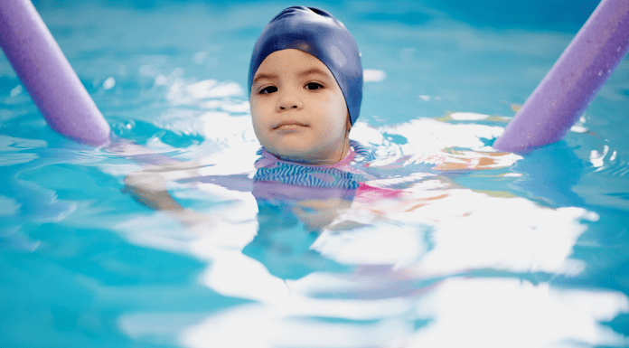 child in a swim cap in a pool during swim class