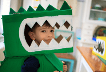 DIy Halloween costume. Young boy wearing a green cardboard dinosaur costume.