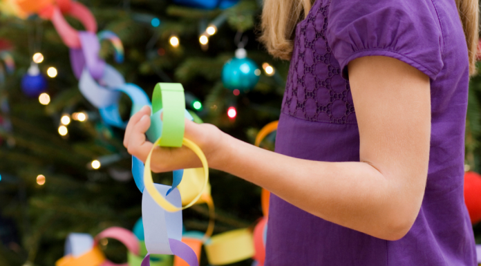 Girl with a paper chain near a Christmas Tree