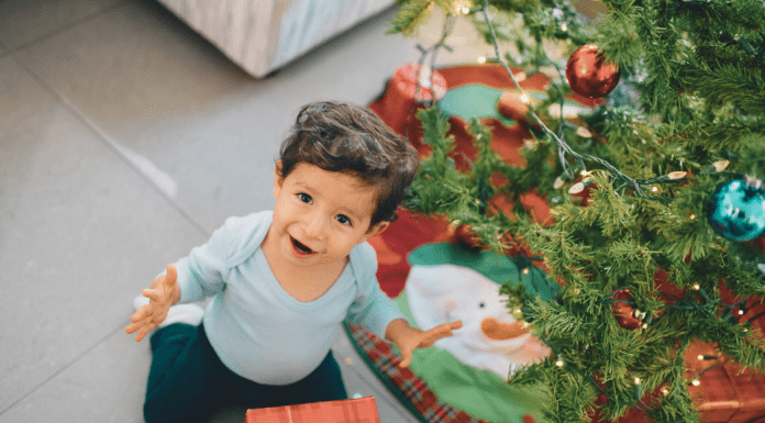 Toddler boy sitting in front of a Christmas tree