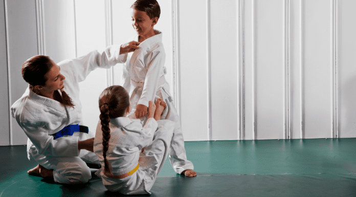 Female jiu jitsu instructor teaching a young students open guard position.