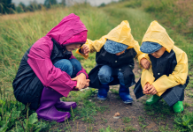 nature experiences featured image. Kids in rain jackets looking at a snail while hiking.